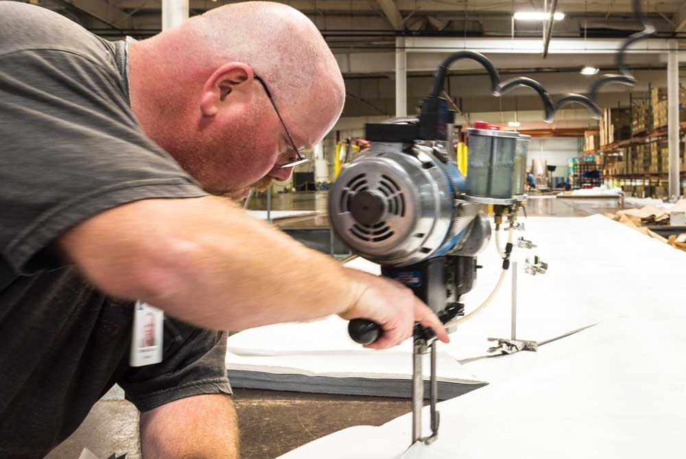 Kappler worker cutting protective suit fabric on a factory cutting table