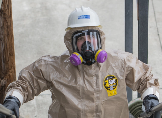 Worker in Kappler Zytron 300 suit, hard hat and full-face respirator with purple cartridges