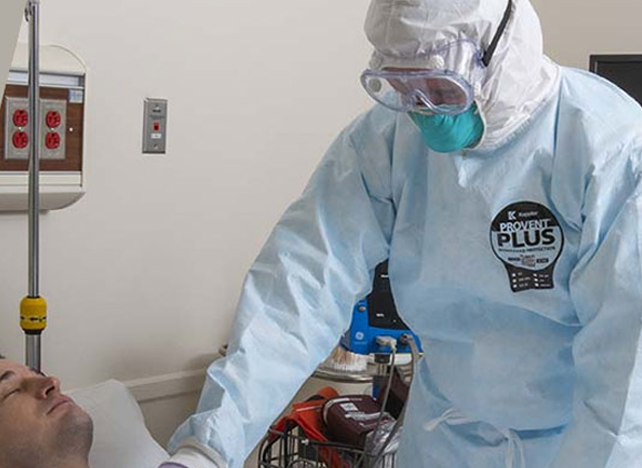 Medical worker in a Kappler ProVent Plus suit, goggles and mask attending a patient at bedside