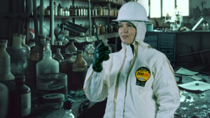 Woman in white Kappler Zytron 300 FR suit holding a chemical bottle in a lab