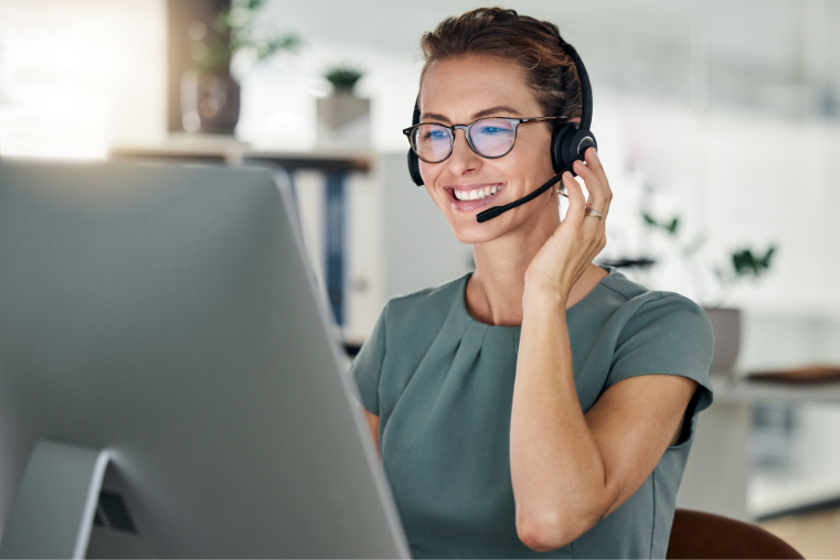 Smiling customer service representative wearing a headset at a computer