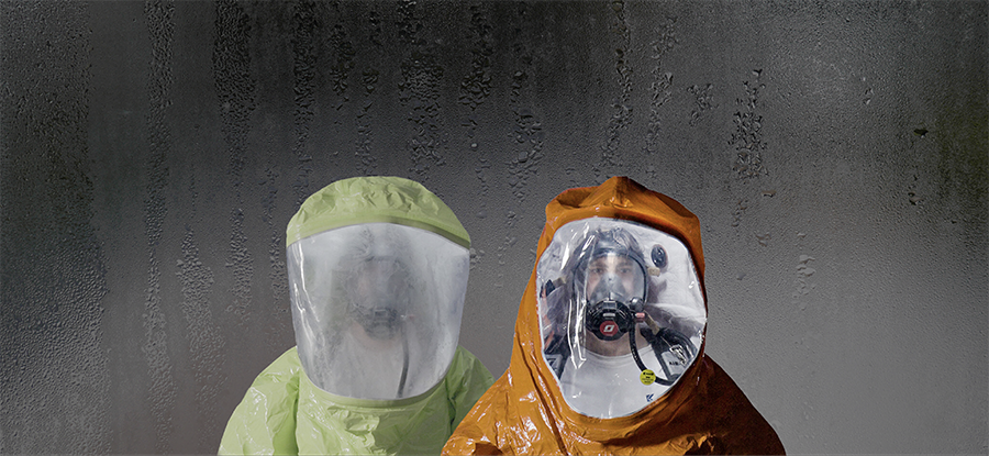 Two hazmat hoods with clear AntiFog visors staying fog-free against a condensation-covered wall