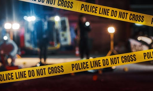 Yellow Police Line Do Not Cross tape at a nighttime emergency response scene